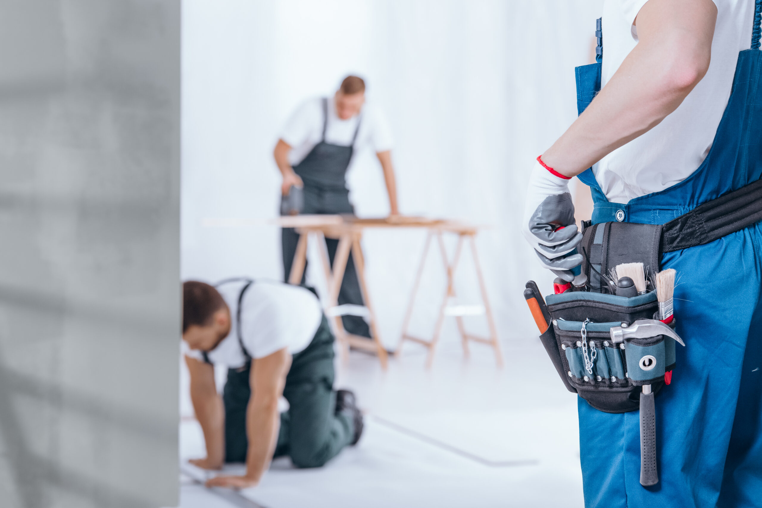 Nahaufnahme eines Handwerkers mit Handschuhen und Werkzeuggürtel während der Renovierung des Hause.